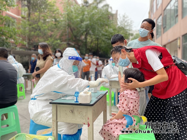 志愿者简国勤（穿红马甲）在辅助孩子做核酸.jpg